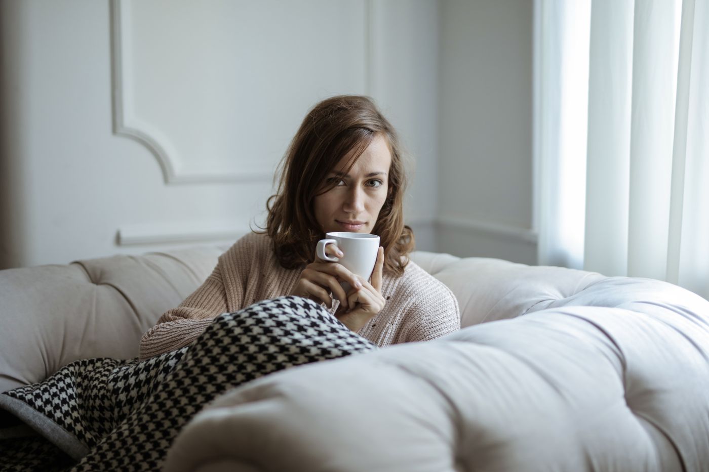 Une femme prend un café, détendue, chez elle