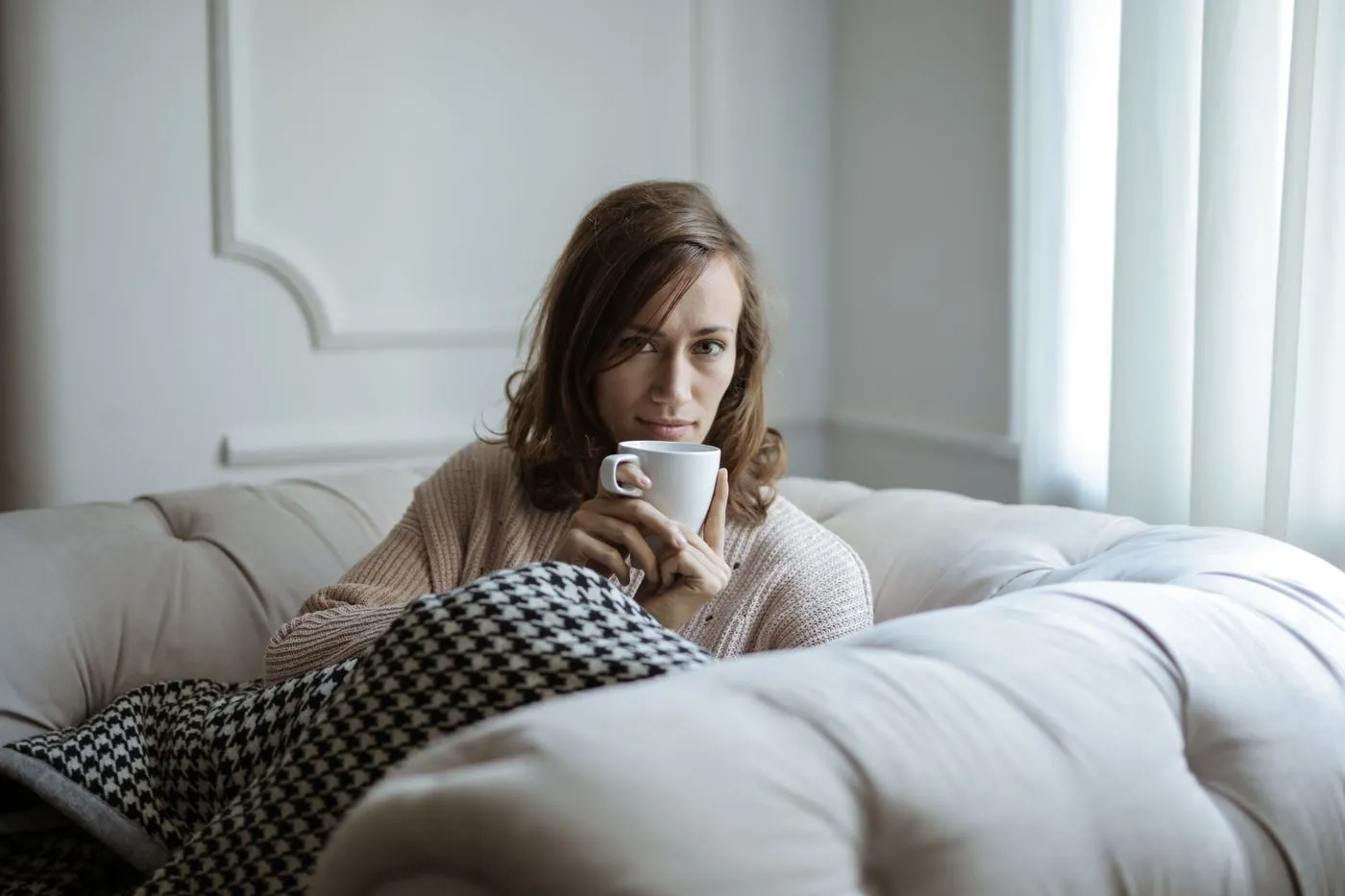 Une femme prend un café, détendue, chez elle
