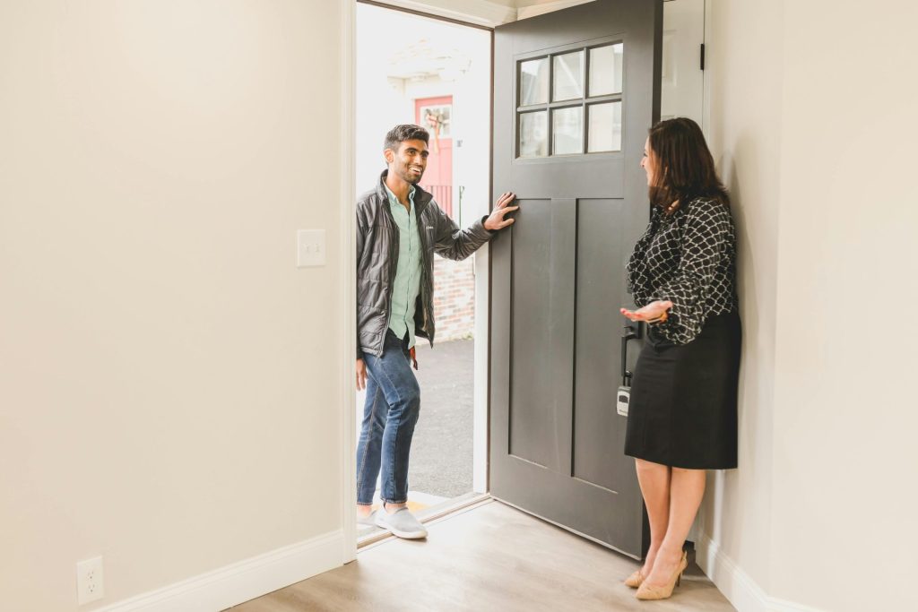 Real estate agent greeting a client at the entrance of a new home, symbolizing a welcoming embrace for potential buyers.